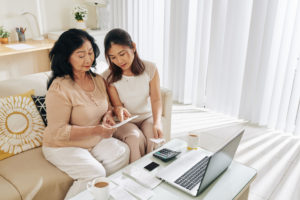 Young Asian woman helping mother at laptop computer 