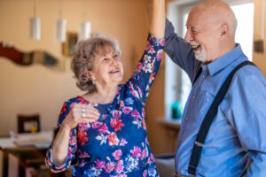 Happy senior couple dancing together at home