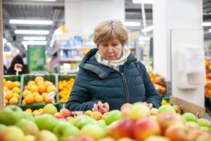 Senior woman picking out an apple at the grocery store 