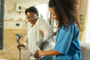 Nursing helping elderly patient with crutches 