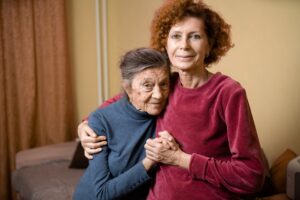 Elderly woman with dementia smiles with caregiver daughter 