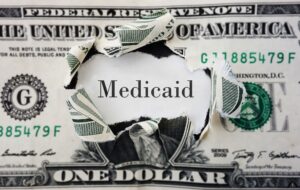 Dollar bill ripped to reveal the word Medicaid 