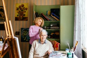 Woman brushes hair of her senior mother at home